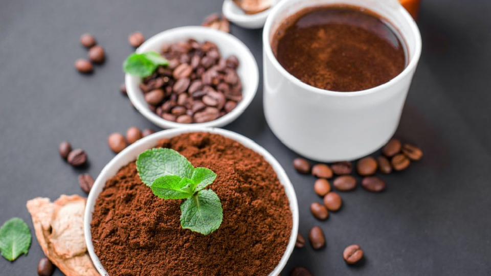 A cup of coffee with cordyceps mushrooms and fresh coffee beans and grounds